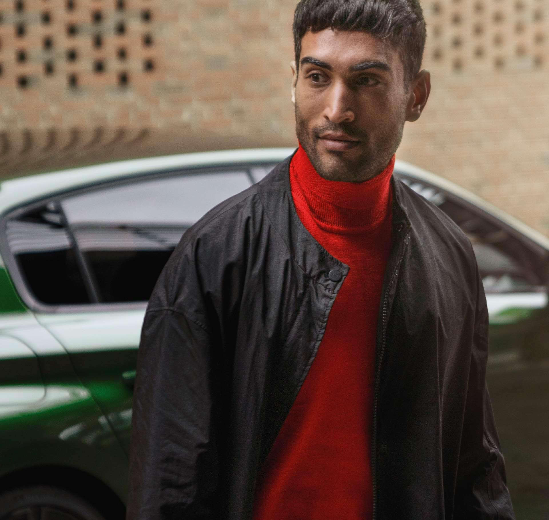 Чоловік у червоній водолазці йде від автомобіля Peugeot вулицею